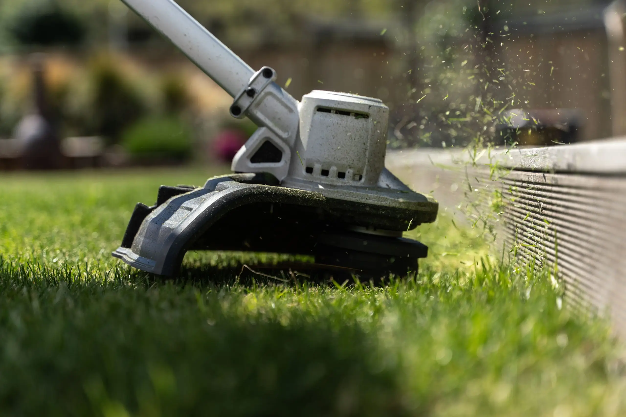 A string trimmer edging neatly along the border of a healthy lawn